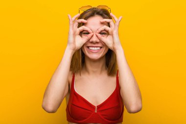 Bikini ve güneş gözlüğü takan beyaz bir kadın gözlerinde iyi bir işaret gösteriyor.