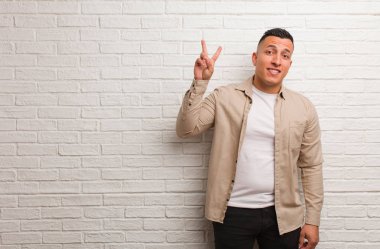 Young latin man fun and happy doing a gesture of victory