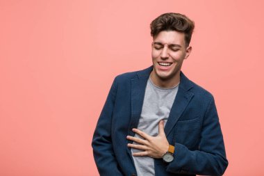 Genç iş adamı mutlu bir şekilde güler ve ellerini karnının üstüne koyarak eğlenir..