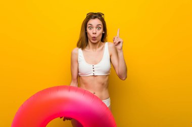 Young woman wearing bikini holding an inflatable donut having some great idea, concept of creativity.