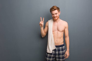 Kızıl saçlı genç bir adam havluyla eğleniyor ve zafer jesti yapıyor. Elinde beyaz bir havlu var..