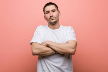 Hoşnutsuzca kaşlarını çatan, kollarını kavuşturan genç bir adam..