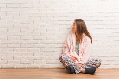 Önüne bakan pijama giyen genç bir kadın.