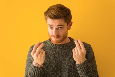 Genç kızıl saçlı adam yakın plan çekimde ihtiyaç jesti yapıyor.