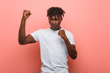 Genç Afrikalı siyah adam zaferden sonra yumruğunu kaldırıyor, kazanan konsept..