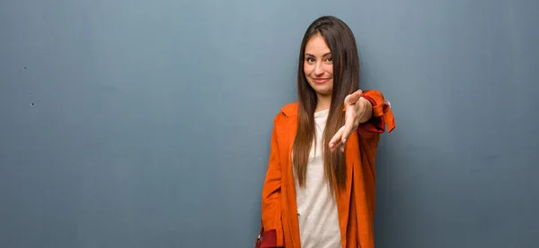 Young natural woman reaching out to greet someone