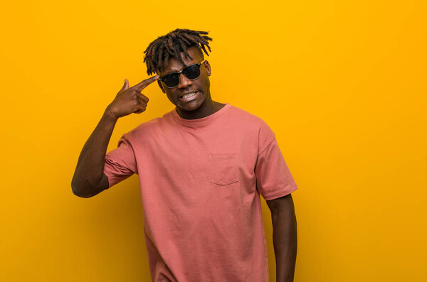 Young casual black man wearing sunglasses showing a disappointment gesture with forefinger.