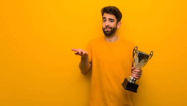 Elinde kupa tutan genç adam kafası karışmış ve şüpheli.