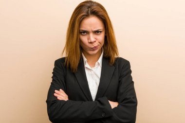 Young caucasian business woman frowning her face in displeasure, keeps arms folded.