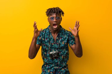 Tatil giymiş genç siyah Rasta adam zaferi ya da başarıyı kutluyor.