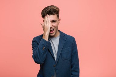 Genç iş adamı yüzünün yarısını avuç içi ile örterek eğleniyor..