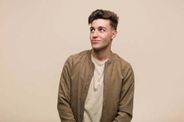 Kahverengi ceketli genç beyaz adam hedeflerine ve amaçlarına ulaşmayı hayal ediyor.