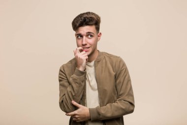 Kahverengi ceket giyen genç beyaz adam rahatlamış fotokopi odasına bakan bir şey düşünüyor..