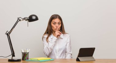 Masasında çalışan genç bayan bir sır saklıyor ya da sessizlik istiyor.