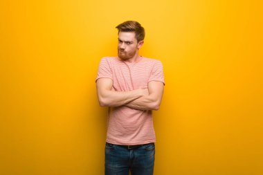 Genç kızıl saçlı adam kollarını kavuşturuyor.