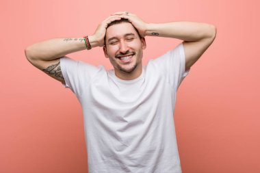 Genç, sıradan bir adam ellerini başının üstünde tutarak neşeyle güler. Mutluluk kavramı.