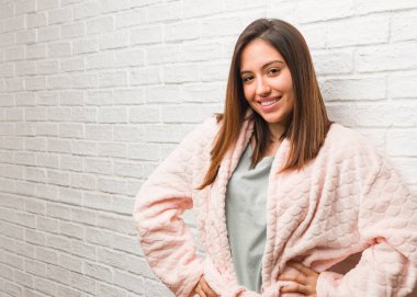 Kalçasında elleri olan pijama giyen genç bir kadın.