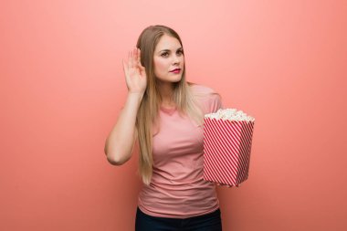 Genç, güzel Rus kız bir dedikoduyu dinlemeye çalışıyor. Elinde patlamış mısır tutuyor..