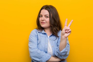 Genç kıvrımlı artı boyutu kadın parmakları ile iki numara gösteren.