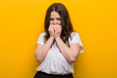 Genç, kıvrımlı, kilolu bir kadın bir şeye gülüyor, elleriyle ağzını kapatıyor..