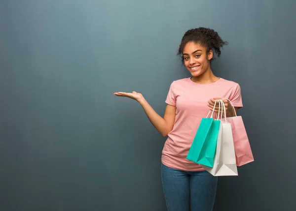Young black woman holding something with hand. She is holding a shopping bags.