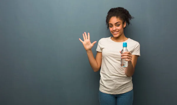 Молодая Черная Женщина Показывает Номер Пять Держит Бутылку Водой — стоковое фото