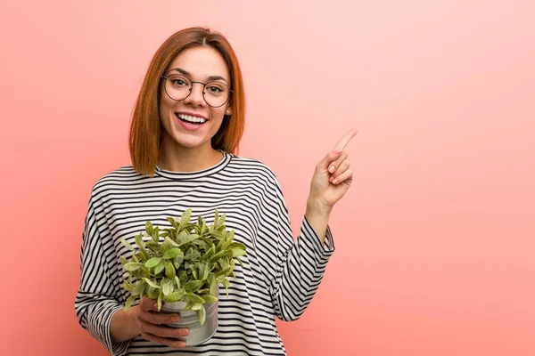 Jonge Vrouw Met Een Plant Glimlachend Vrolijk Wijzend Met Wijsvinger — Stockfoto