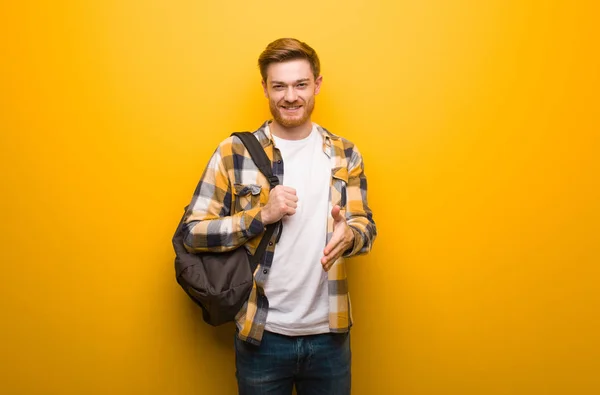 Young redhead student man reaching out to greet someone