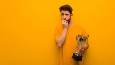 Elinde kupa tutan genç bir adam tırnak yiyor, gergin ve çok endişeli.