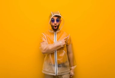 Yan tarafı gösteren yağmurluk giyen genç bir adam.