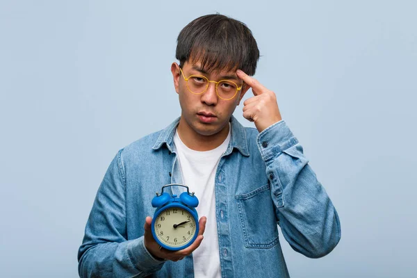 Young Chinese Man Holding Alarm Clock Thinking Idea — Stock Photo, Image
