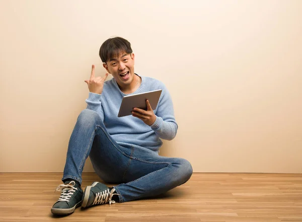 Jovem Chinês Sentado Usando Seu Tablet Fazendo Gesto Rocha — Fotografia de Stock