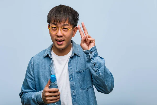 Jovem Chinês Segurando Uma Garrafa Água Divertido Feliz Fazendo Gesto — Fotografia de Stock