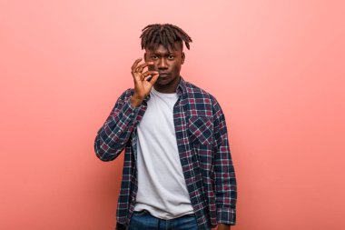 Dudaklarında bir sır tutan parmakları ile genç Afrikalı siyah adam.