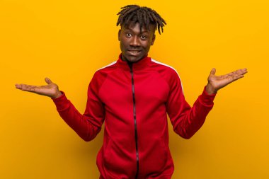 Genç fitness siyahi adamın kafası karışık ve şüpheci. Kopya alanını tutmak için ellerini kaldırıyor..