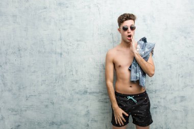 Mayo giyen genç beyaz adam gizli bir sıcak fren haberi veriyor ve yan bakıyor.