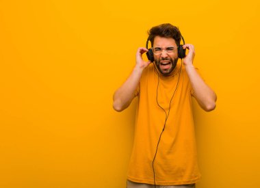 Genç adam müzik dinliyor kulaklarını elleriyle kapatıyor.