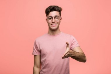 Genç, havalı, beyaz bir adam selamlama jesti için kameraya elini uzatıyor..