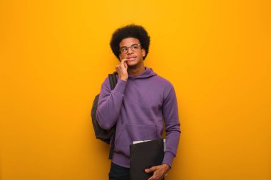 Genç Afrikalı Amerikalı öğrenci rahatlamış fotokopi odasına bakan bir şey düşünüyor.