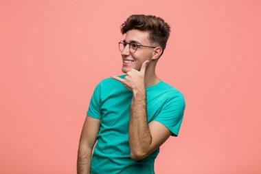 Genç, havalı, beyaz bir adam cep telefonu hareketini parmaklarıyla gösteriyor..