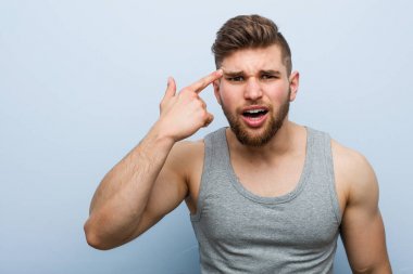 Genç yakışıklı fitness adamı işaret parmağıyla hayal kırıklığı jesti yapıyor..