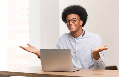 Genç siyahi adam gelmek için bilgisayarını kullanıyor.