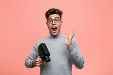 Genç entelektüel adam elinde bir film kamerasıyla zaferi ya da başarıyı kutluyor.