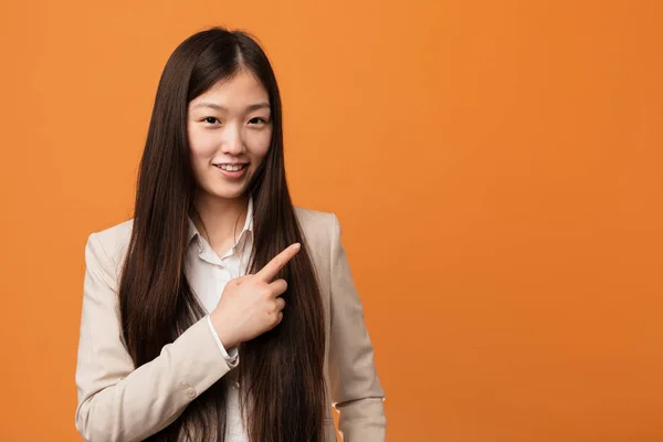 Young business chinese woman smiling and pointing aside, showing something at blank space.