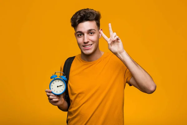 Young Student Man Holding Alarm Clock Looking Sideways Doubtful Skeptical — 스톡 사진