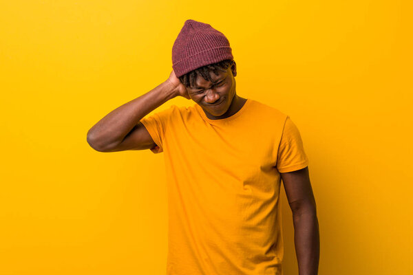 Young black man wearing rastas over yellow background suffering neck pain due to sedentary lifestyle.