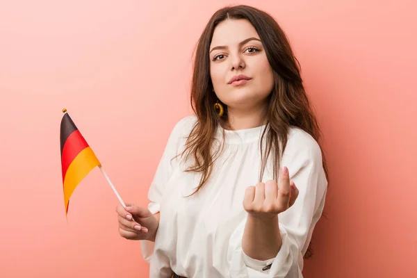 若いですCurvyプラスサイズ女性を保持していますドイツのフラグポインティングとともに指であなたに近づいてくる — ストック写真