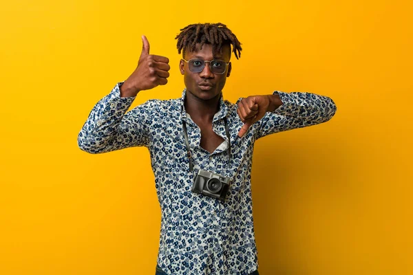 Tatil kıyafeti giyen genç siyah Rasta adam baş parmağını kaldırıyor, zor seçim konsepti.