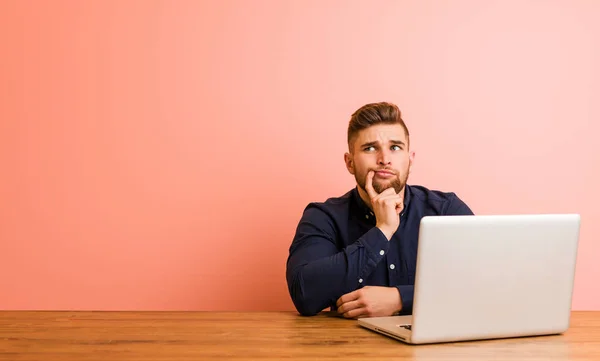 Jongeman Werkt Met Zijn Laptop Kijken Zijwaarts Met Twijfelachtige Sceptische — Stockfoto