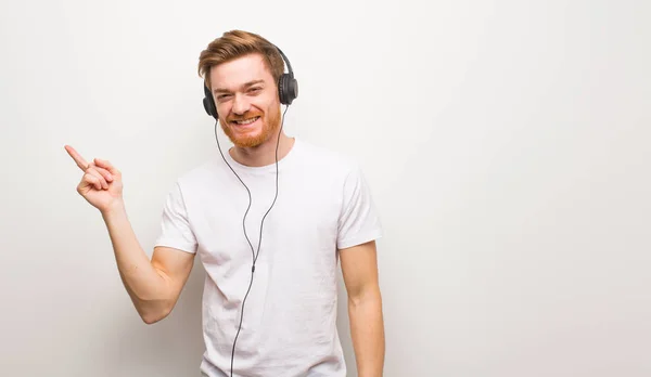 Ung Rödhårig Man Som Pekar Sidan Med Fingret Lyssna Musik — Stockfoto